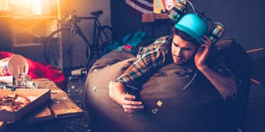 man laying down on a bean bag drunk texting someone