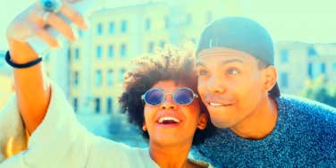 woman taking selfie with a man who is using her for an ego boost