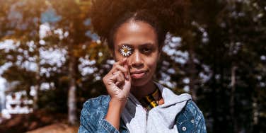 woman holding flower in front of eye