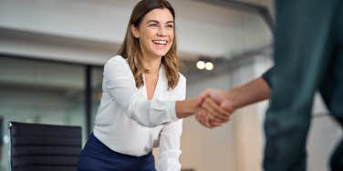 Happy business woman shaking hand of boss during job interview in office