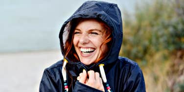 redhead woman with freckles laughing in raincoat