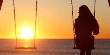 woman on swingset with sunset