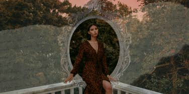 Hopeless romantic in red dress sitting on balcony outside 