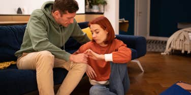 woman sitting on the floor comforted by man