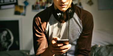 teenage boy with headphones, looking at a phone