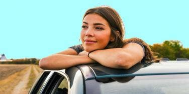 smiling woman looking out of car window thinking of her long distance relationship
