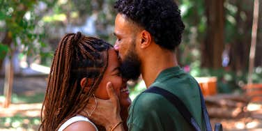 man kissing woman's forehead