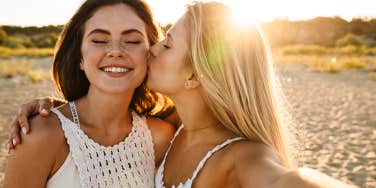 Two young happy women smiling and taking selfie photo while walking on beach