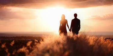 woman and man holding hands in sunset