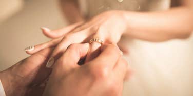 groom putting ring on bride's finger