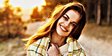 young woman joyfully looks at camera, light behind her hair