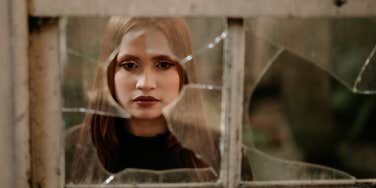 woman looking through broken window
