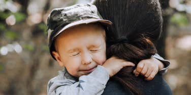 squinting boy hugging woman