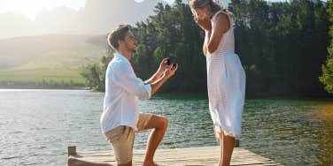 man proposing to woman on dock on lake