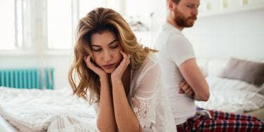 woman looking distraught with husband in background