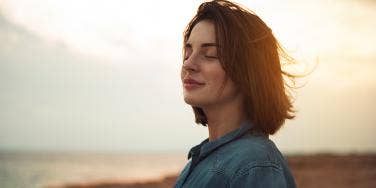 woman looking out at world with sunset behind her