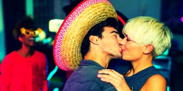 woman kissing man in a sombrero