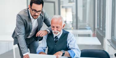 Boss helps older employee with his computer. 