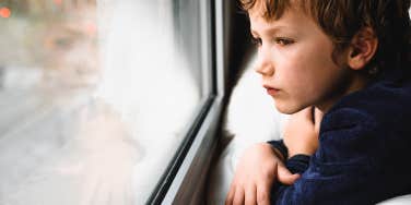 sad child looking out the window