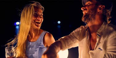 man and woman enjoying drinks at night laughing together