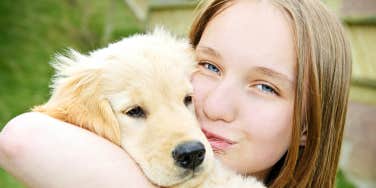 teenage girl holding and kissing a dog
