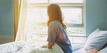 mom sitting on bed looking out window