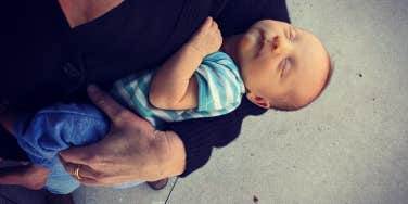 A woman's arm holding a newborn baby, both caucasian 