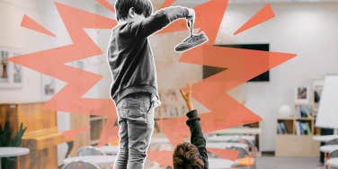 Little boy holding other Childs shoe over his head on desk