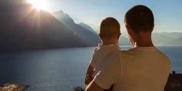 father holding baby looking at water