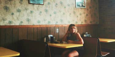 Young girl sitting at diner, upset