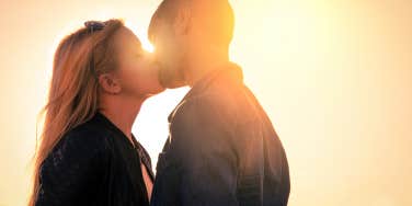woman and man kissing in sunset