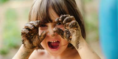 child with mud on hands