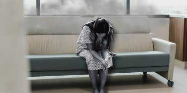 Woman sitting in hospital gown, sad