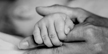newborn holding mother's hand