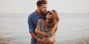 couple holding each other in front of the water