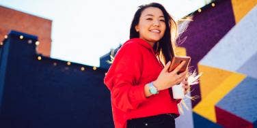 woman in red smiling looking at iphone