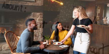 Couple at restaurant, waitress serving them food