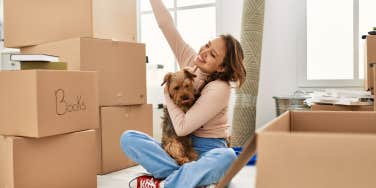 young woman moving into apartment sitting on floor with boxes
