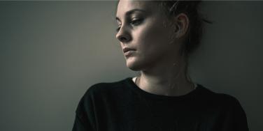 photo os sad woman in black shirt against wall