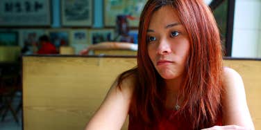 unhappy girl sitting in booth at restaurant