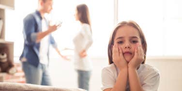 upset child with fighting parents in background