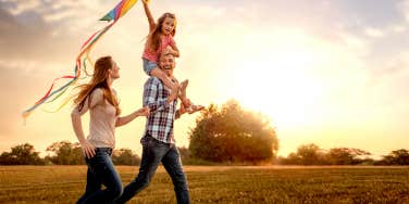 family running through field letting kite fly