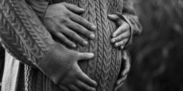 pregnant couple in black and white photo cradling pregnant belly