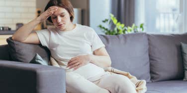 upset pregnant woman sitting on the couch
