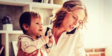 mother talks on phone while holding baby