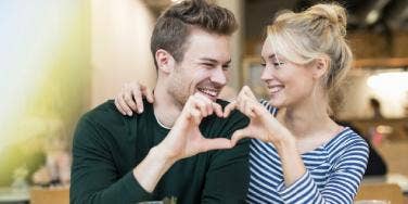 man and woman making heart with their hands