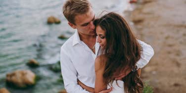 man hugging woman overlooking ocean cliff