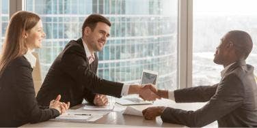 people shaking hands in business setting