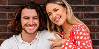 smiling couple against brick wall