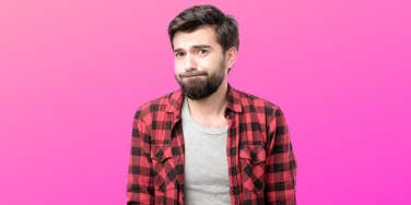 A regretful looking man stand in front of a hot pink background